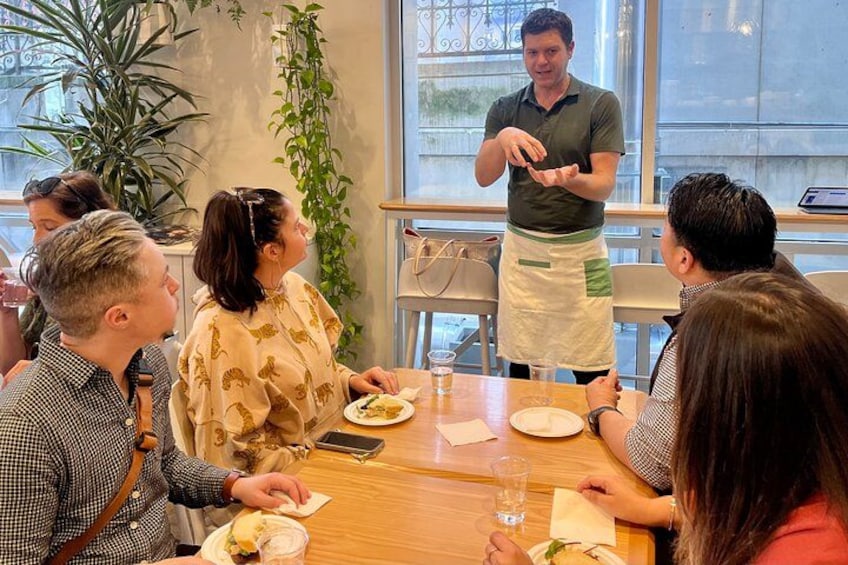A group of people dining at a restaurant with a waiter serving food. 4