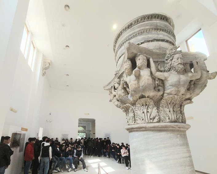 A marble sculpture in a museum with a crowd of visitors. 5