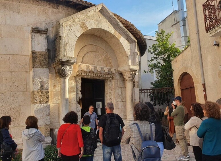 A group of people standing in front of an old stone building with an arched entrance. 2
