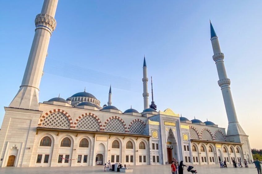 A mosque with multiple minarets and domes, featuring arched windows and decorative patterns. 1