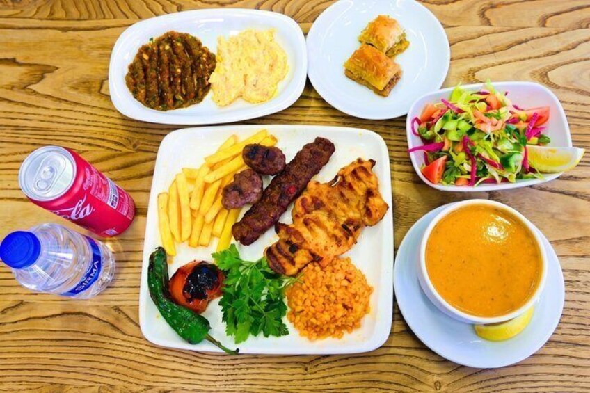 A meal with grilled meat, fries, salad, and a bowl of soup on a wooden table. 2
