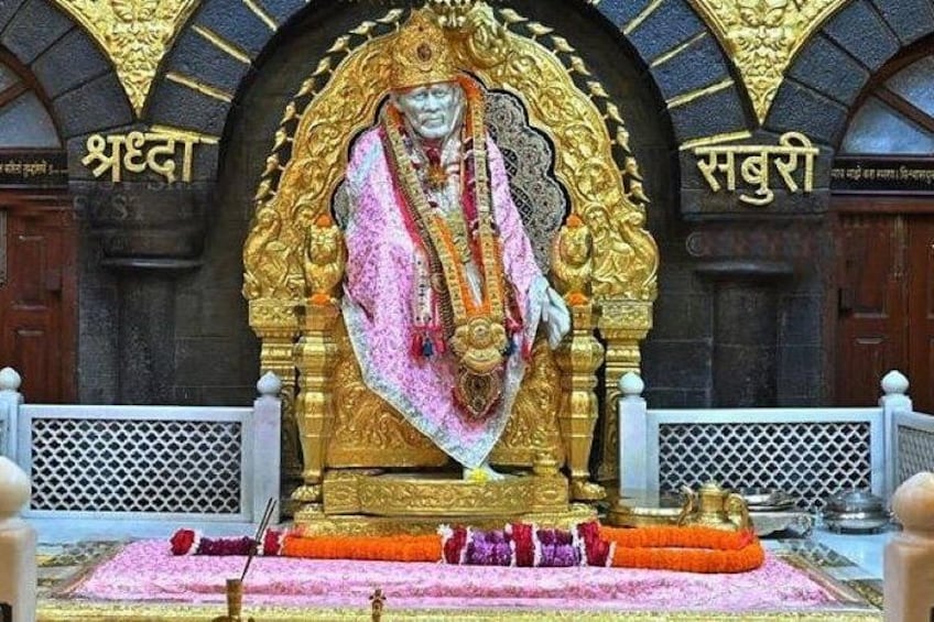A statue of a deity in a temple, with ornate golden decorations and inscriptions in a foreign script. 1
