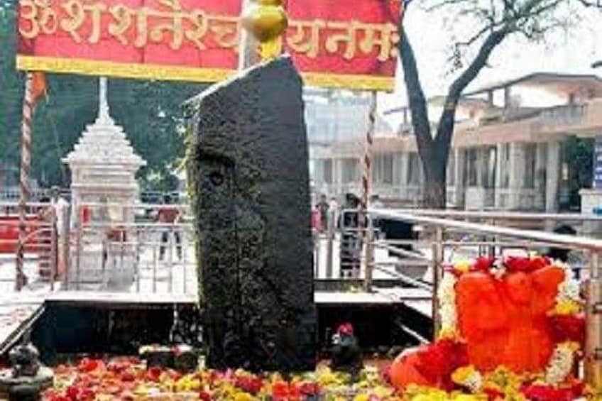 A stone structure with a golden top, surrounded by flowers and a temple in the background. 5