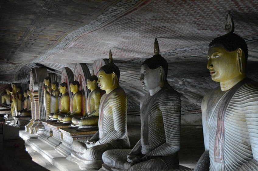 A row of large Buddha statues in a cave. 5