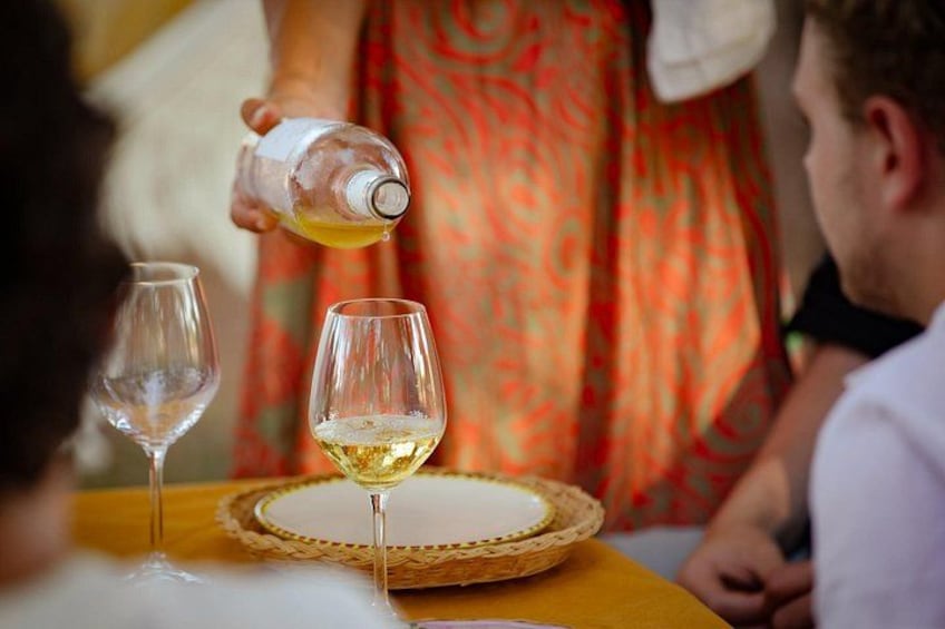 Una persona versa un drink in un bicchiere, con un altro bicchiere e un piatto sul tavolo. 1