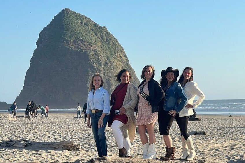 Un groupe de personnes se trouve sur une plage, avec une grande formation rocheuse en arrière-plan. 2