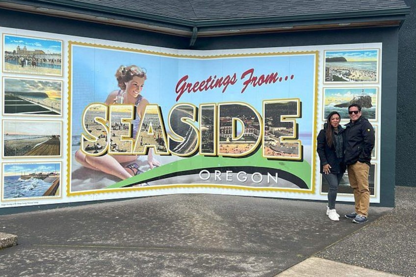 A large outdoor sign with the text 'Greetings From... SEASIDE OREGON' and various scenic images of the coast. 3