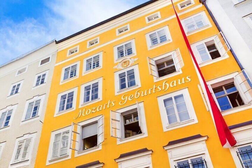 A yellow building with the text 'Mozarts Geburtshaus' and a red flag. 2