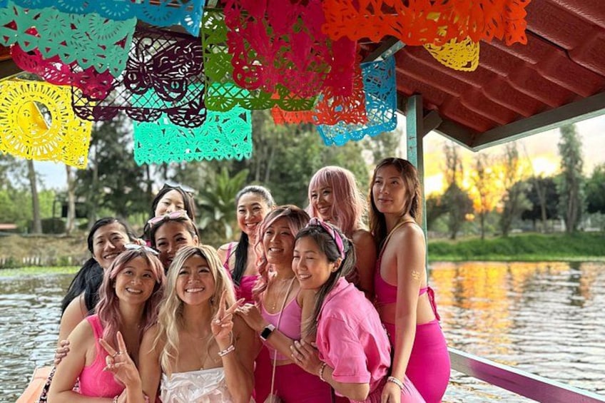 A group of people on a boat with colorful paper decorations overhead. 1