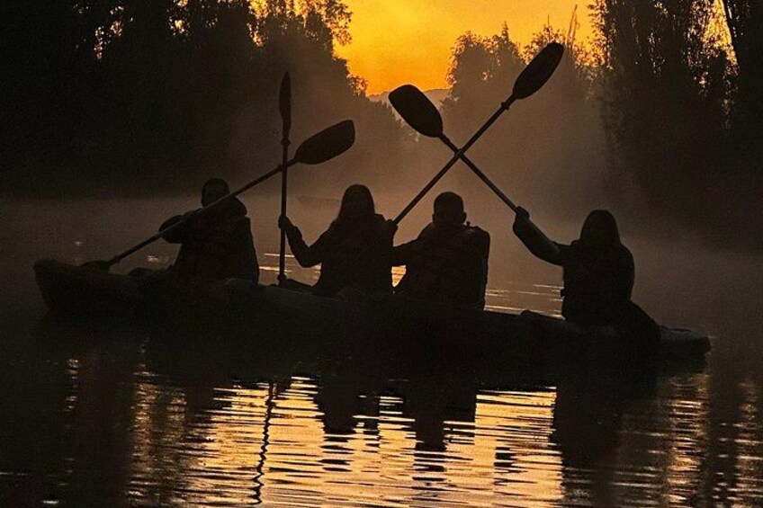 A group of people kayaking in a misty river at sunrise. 4