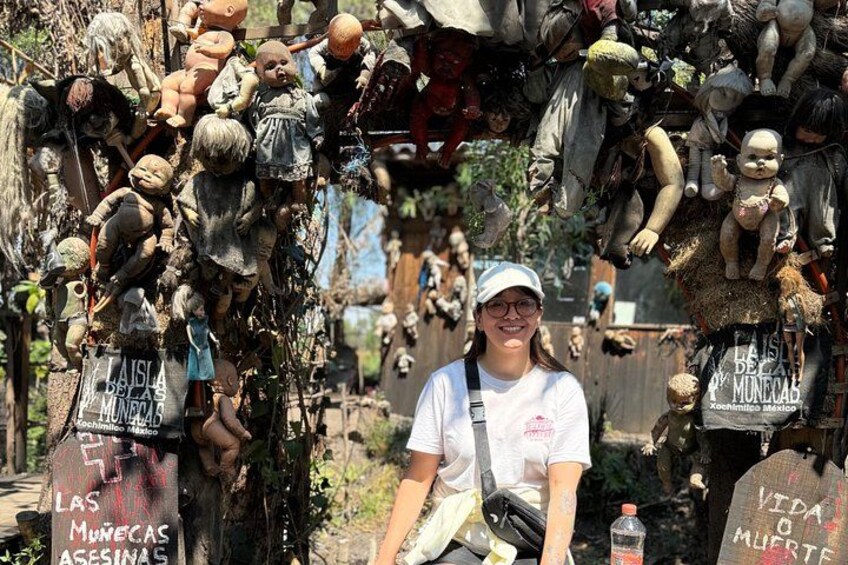 A person standing in front of a collection of dolls and figures, with signs that read 'Las Muñecas Asesinas' and 'Vida o Muerte.' 4