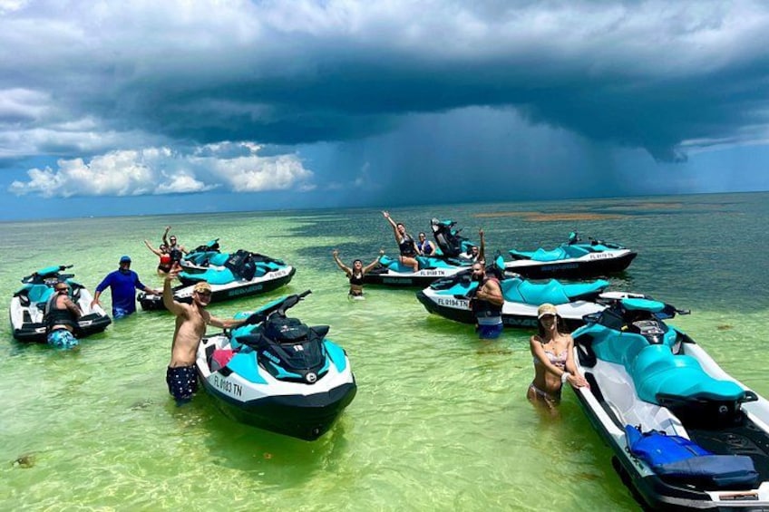 People on jet skis in shallow water with a stormy sky. 1
