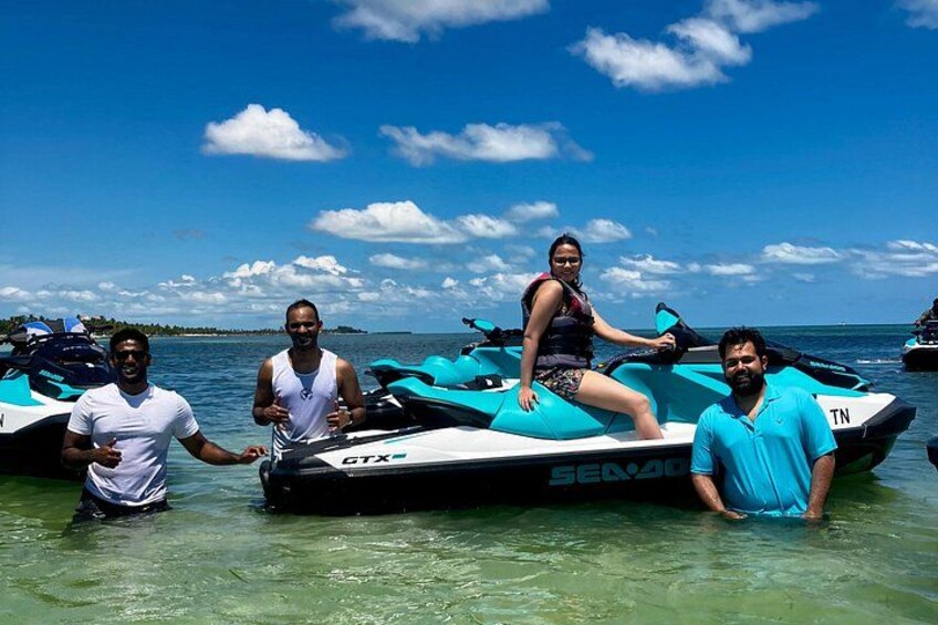 People on jet skis in shallow water with a clear sky and distant land. 3
