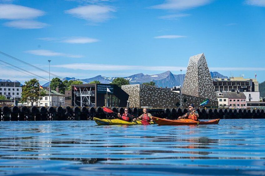 Kayakers on a calm body of water with a distinctive building in the background. 4