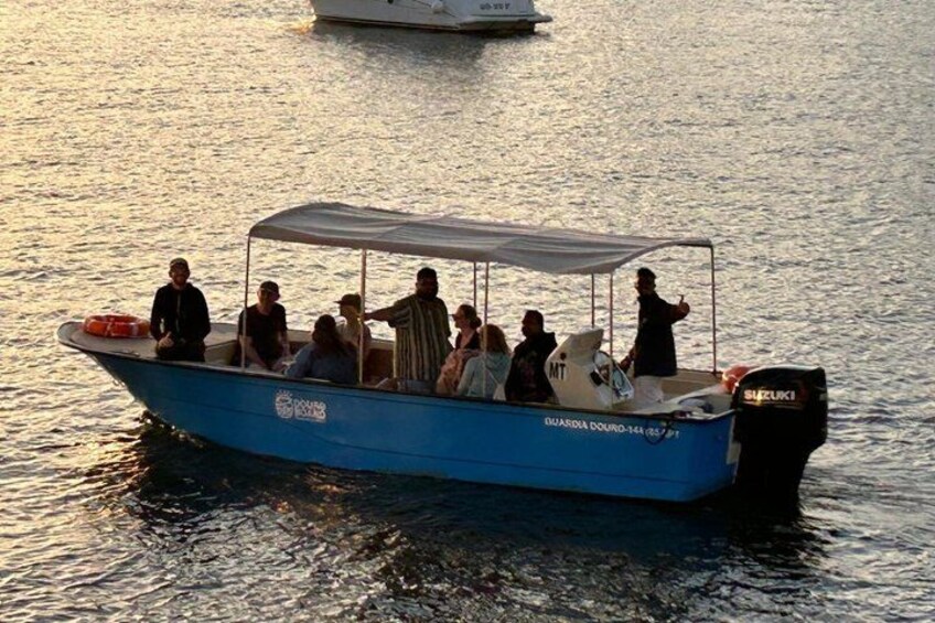 Un bote azul con gente a bordo, un bote blanco al fondo y un motor en la popa. 2
