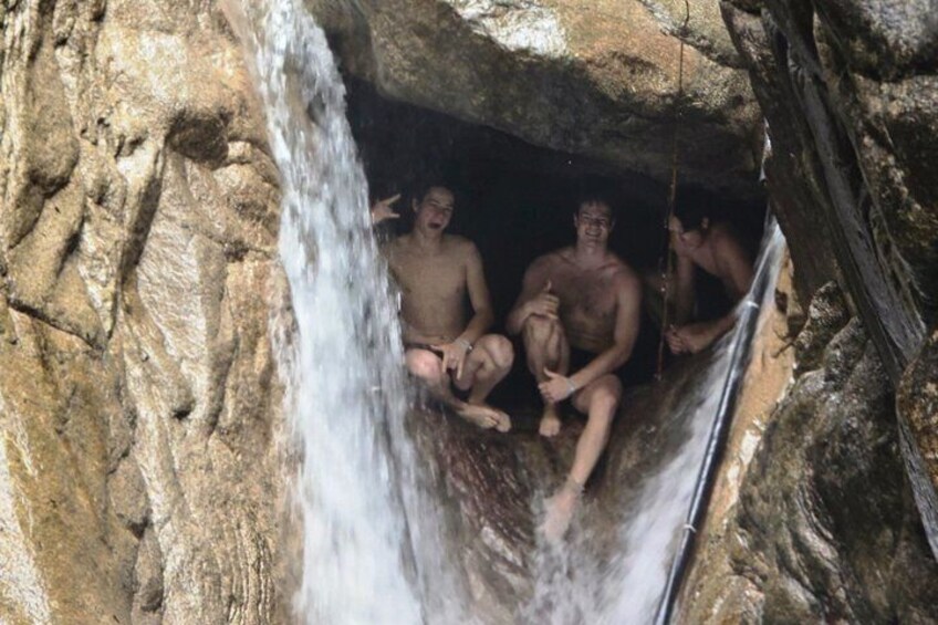 Un groupe de personnes est assis dans une grotte, près d’une cascade. 2