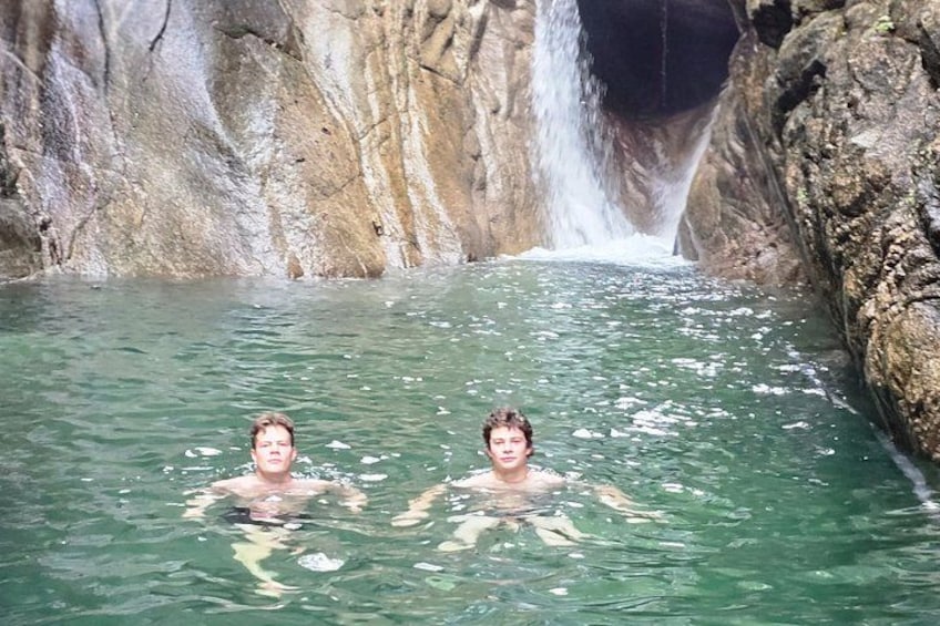 Deux personnes nagent dans une piscine naturelle, avec une cascade en arrière-plan. 5