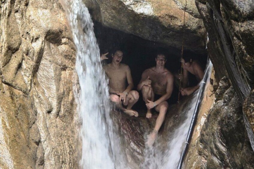 Une grotte avec une cascade et des personnes assises à l’intérieur. 2