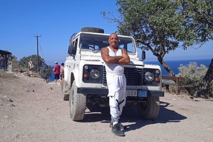 Un vehículo todoterreno blanco estacionado en un camino de tierra, con una persona de pie al frente. 1