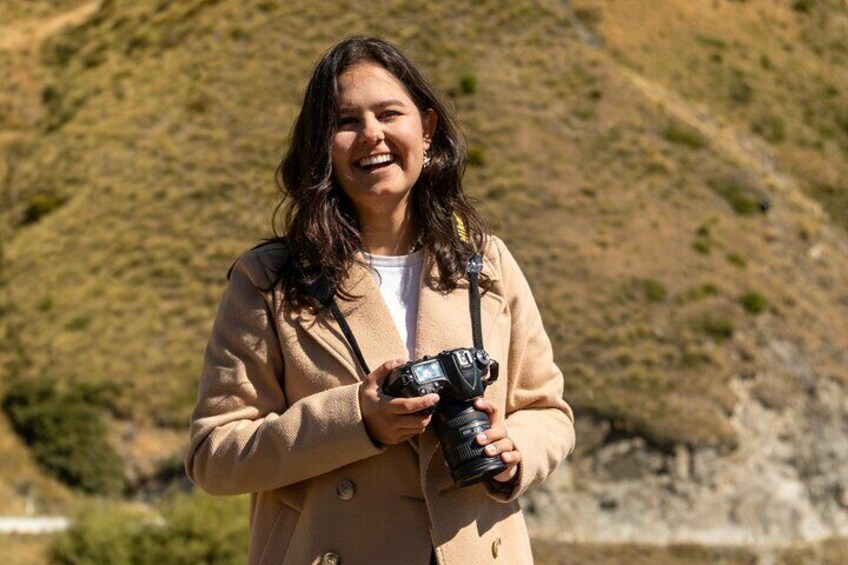 Una persona sosteniendo una cámara con un paisaje montañoso de fondo. 5