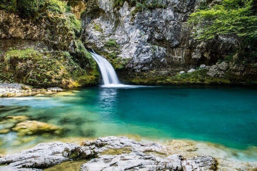 Ein Wasserfall in einer felsigen Schlucht mit klarem, türkisblauem Wasser. 1