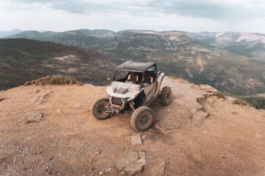 A quad bike parked on a rocky outcrop overlooking a mountainous landscape. 1