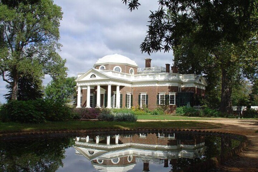 A large brick building with a dome and columns, surrounded by trees and a pond. 2