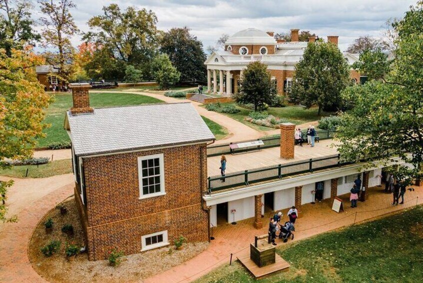 A brick building with a covered walkway, surrounded by trees and a large building in the background. 5