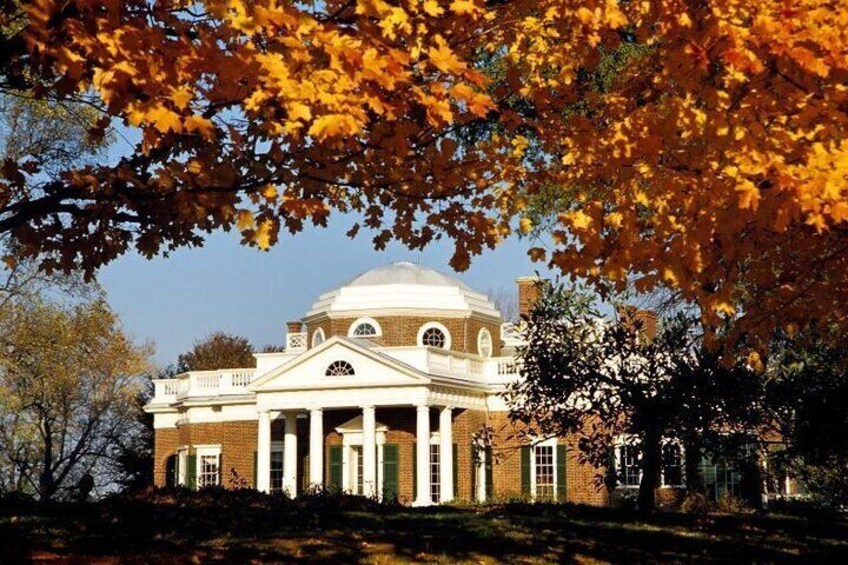 A historic building with a dome and columns, surrounded by autumn foliage. 1