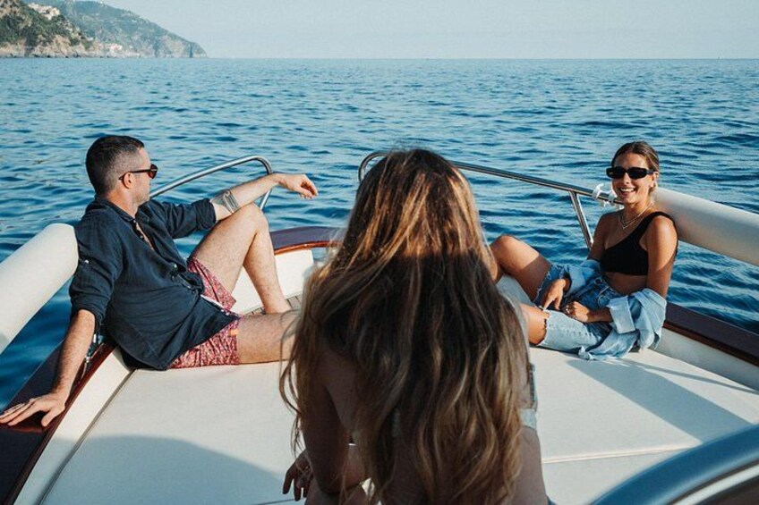 Three people on a boat on a body of water with a coastline in the background. 5