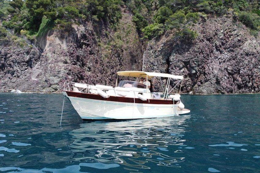 A boat on calm water with a rocky coastline in the background. 4