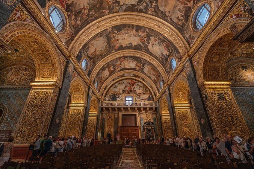 An ornate church interior with high ceilings, detailed frescoes, and a central altar. 5