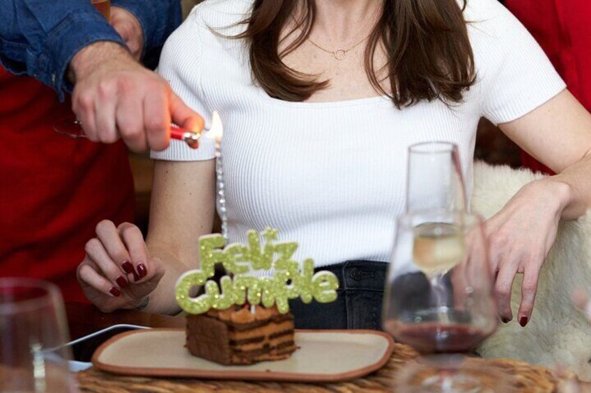 A person lighting a birthday candle on a cake with 'Feliz Cumple' written on it. 1