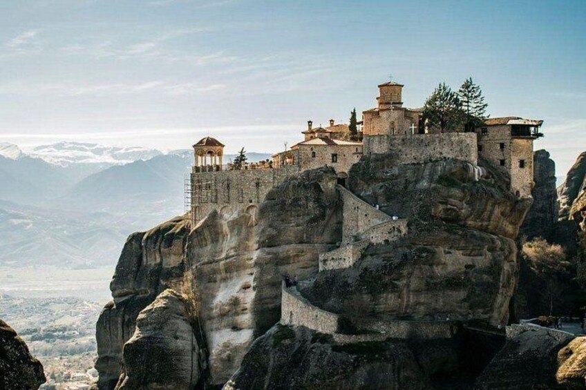 A monastery perched atop a rocky cliff with a panoramic view of the landscape. 1