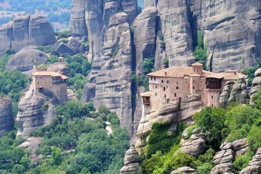 A monastery perched on a rocky cliff surrounded by lush greenery. 4