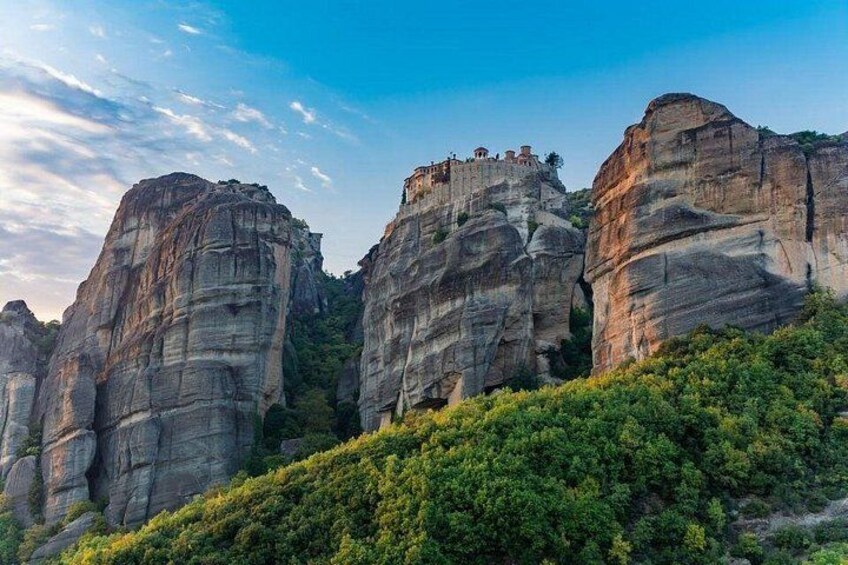 A mountainous landscape with large rock formations and a monastery on top. 3