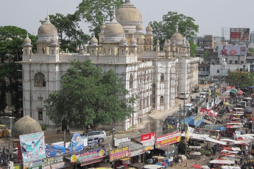 A historic building with domes, surrounded by a busy street with shops and vehicles. 3
