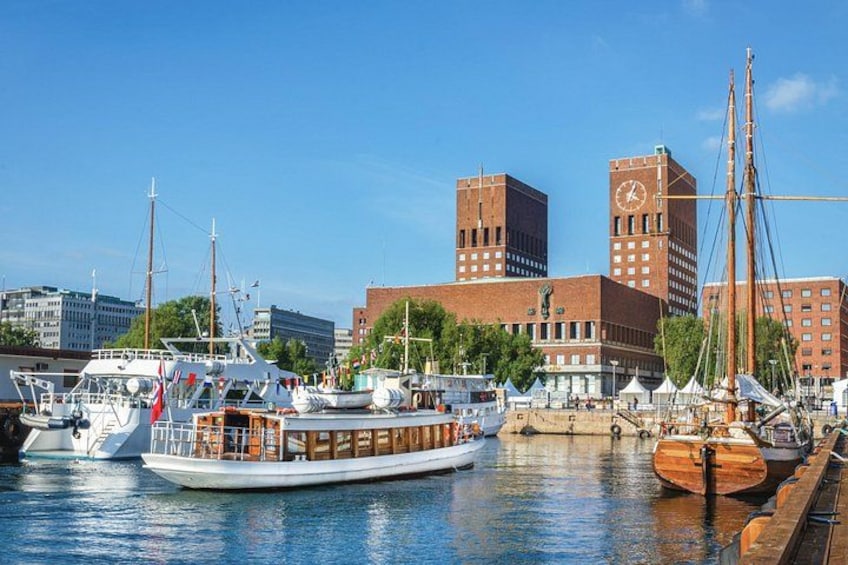 A marina with various boats, including a wooden boat and a white motorboat, docked in the water. In the background, there are tall brick buildings with a clock tower. 3