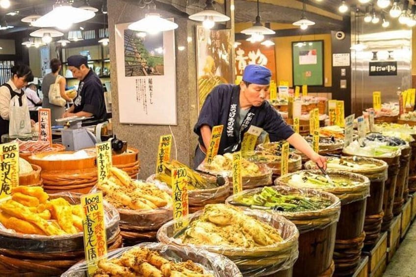 Un puesto de mercado con diversos productos alimenticios, incluyendo mariscos y verduras, exhibidos en recipientes grandes. 4