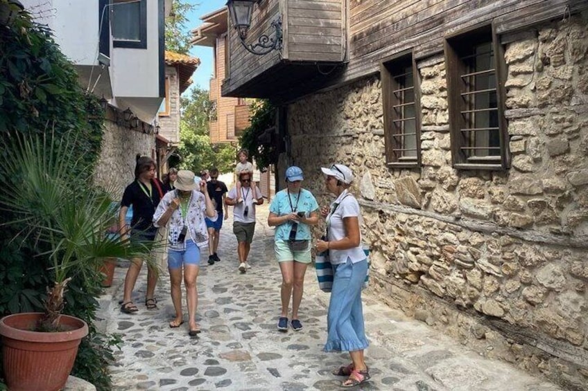 Un groupe de personnes marchant sur un chemin pavé de pierres dans une ruelle étroite, entre deux bâtiments en pierre. 1