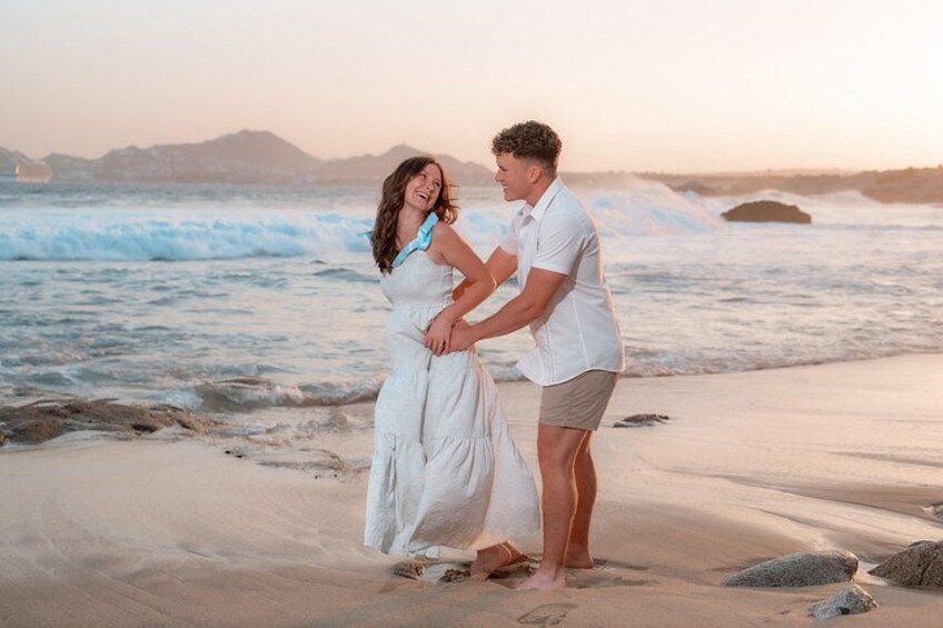 A couple on a beach with waves and a distant mountain range. 5