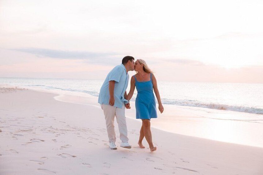 A couple walking on a beach with footprints in the sand. 3