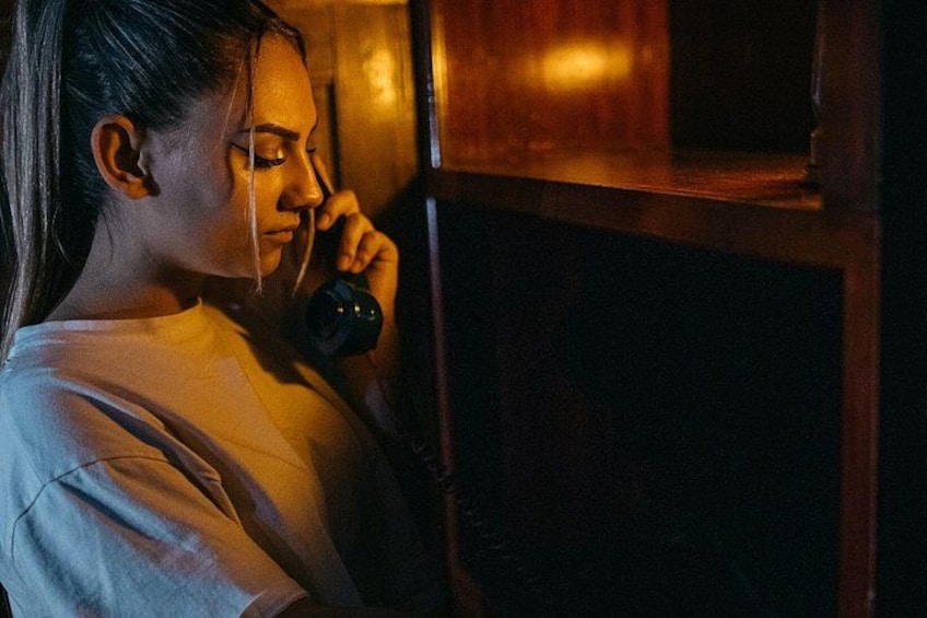 A person holding a phone near a wooden cabinet. 1