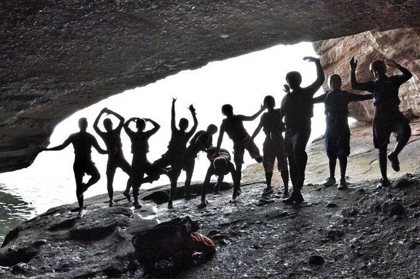 Un grupo de personas en una cueva con paredes rocosas y vista al agua. 3