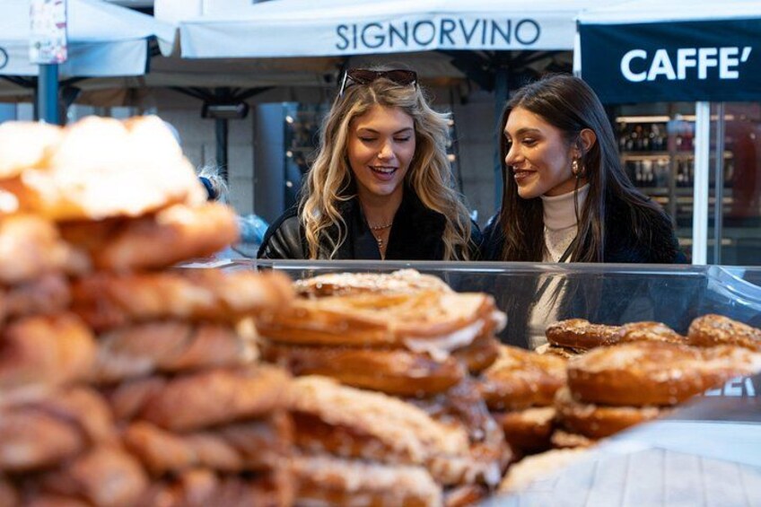 A food stall with pastries and a sign that reads 'SIGNORVINO' in the background. 3