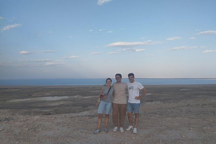 Three people standing on a beach with a vast ocean in the background. 4