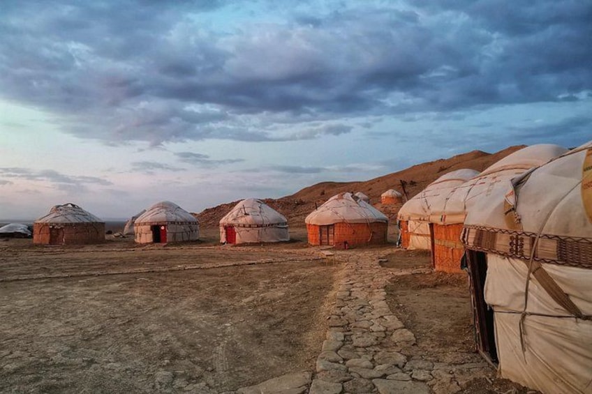 Yurts in a dry, rocky landscape with a stone path leading through them. 1