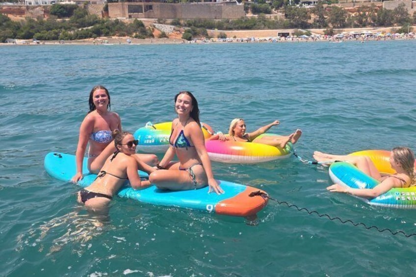 People on inflatable watercraft in a body of water with a coastal landscape in the background. 5