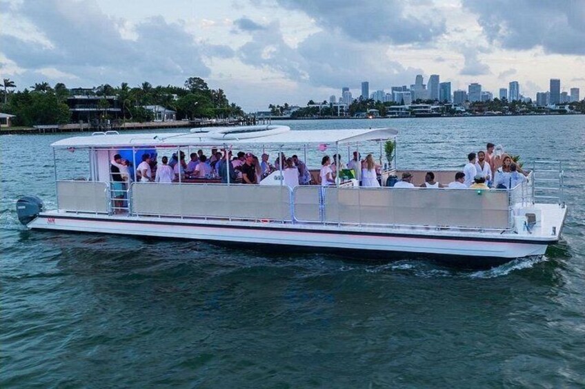 A boat with people on it, water, and a city skyline in the background. 1