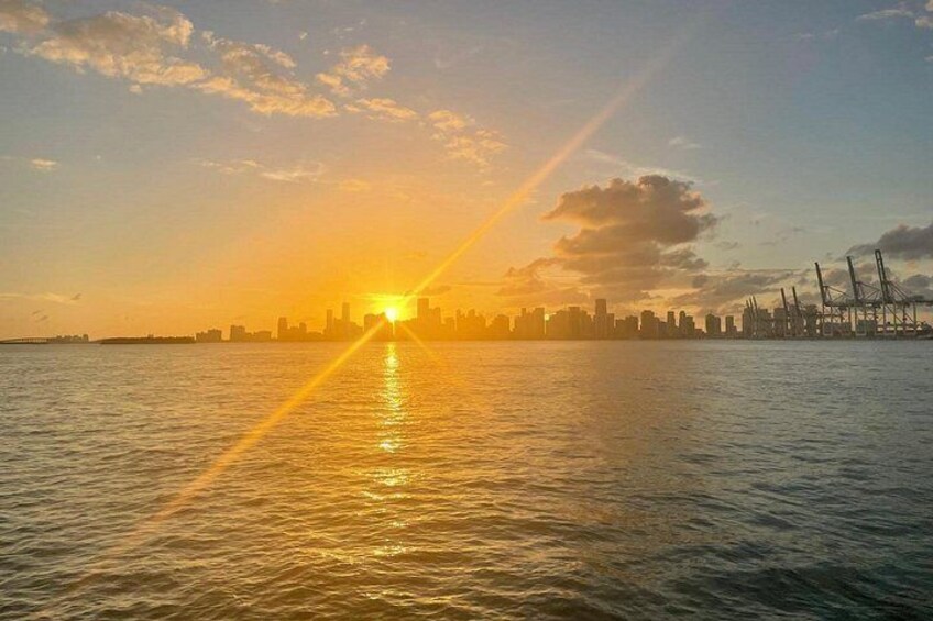 A sunset over a body of water with a city skyline in the background. 3